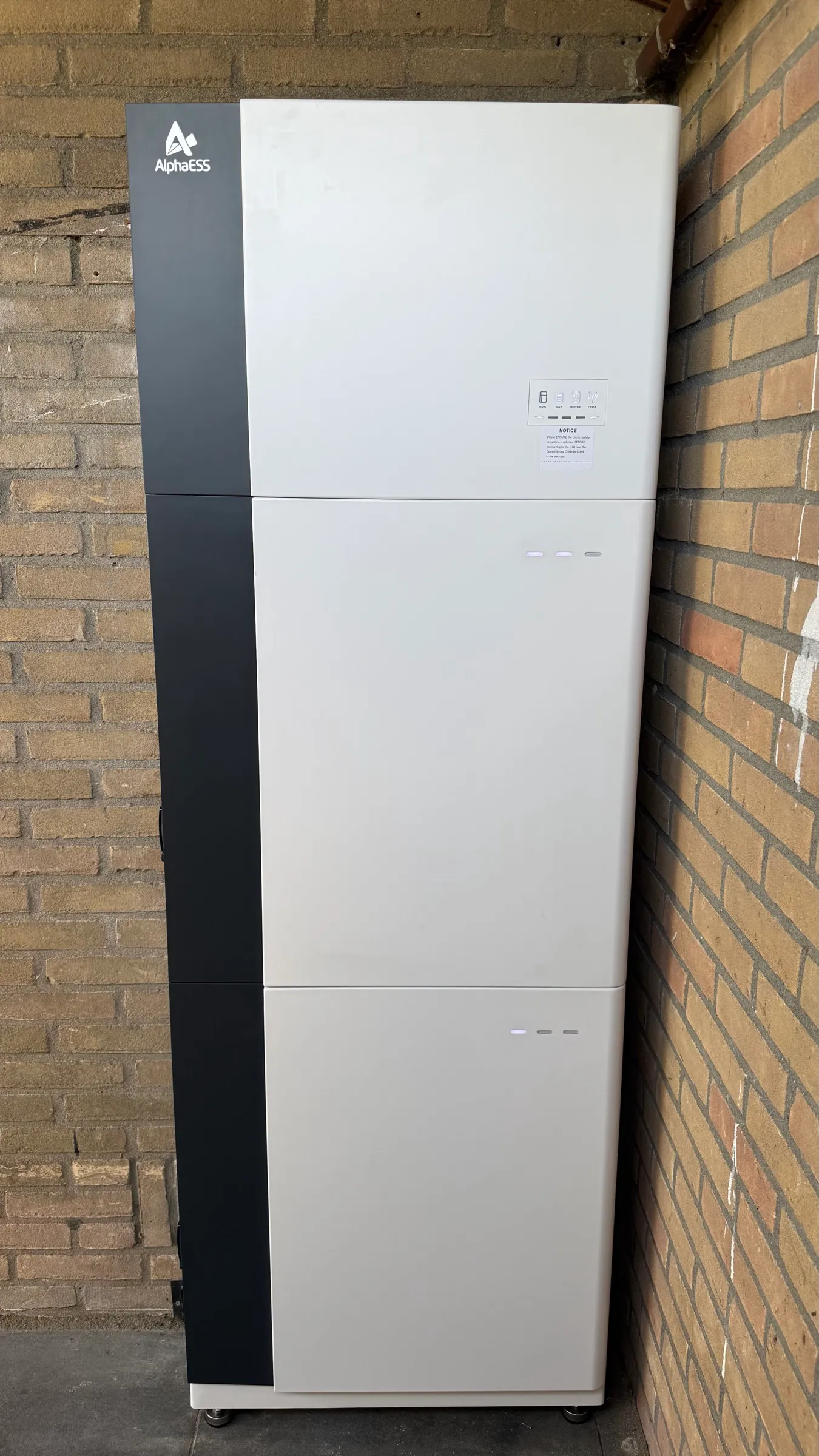 AlphaESS-thuisbatterij van 18,6 kWh: omvormer en twee witte batterijmodules tegen een bakstenen muur