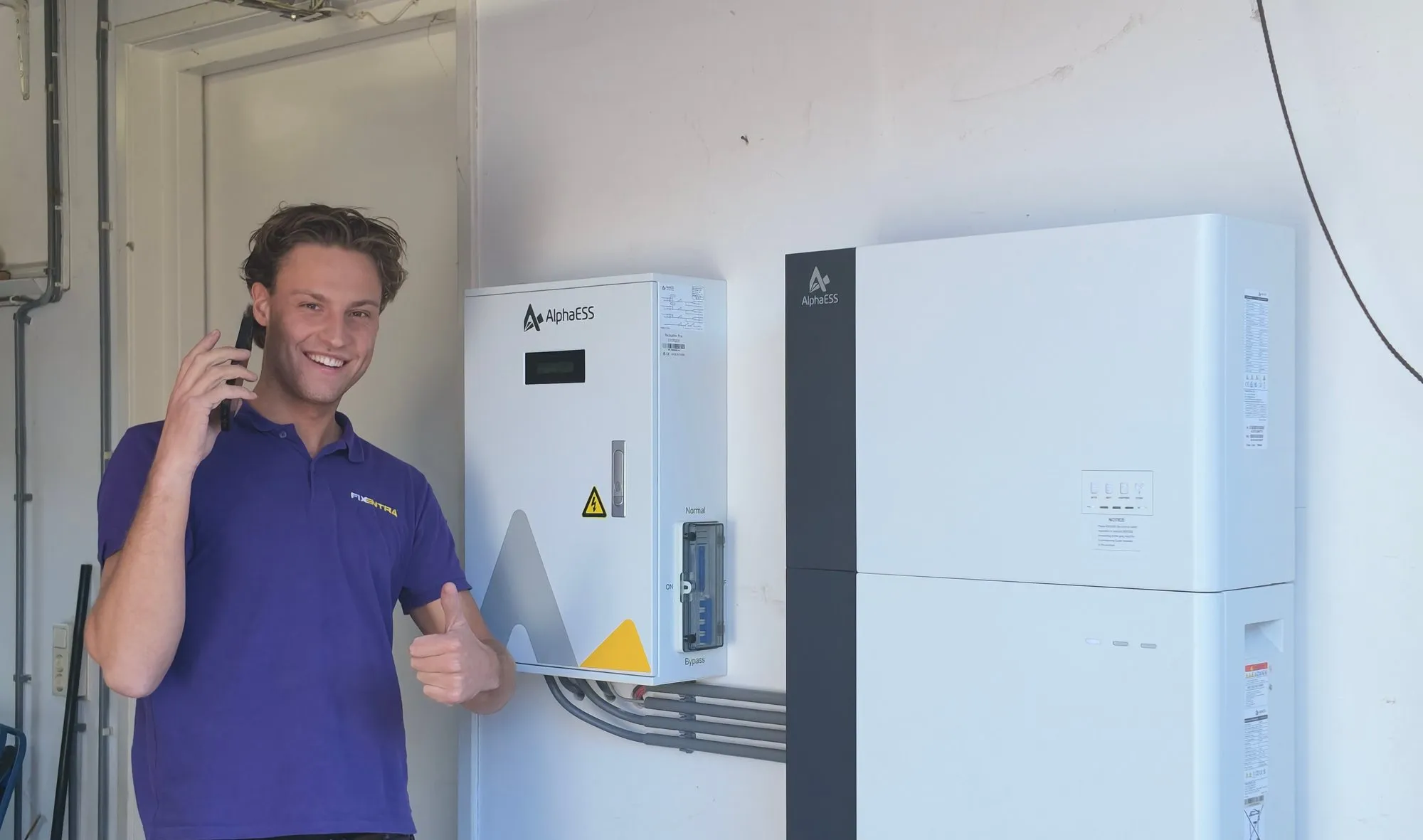 Een elektricien van Fixentra steekt zijn duim op naast een AlphaESS Backup Box Plus en een thuisbatterij van 18,6 kWh
