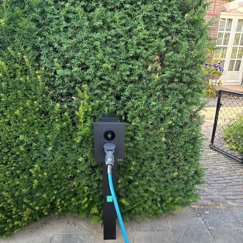 Laadpaal op een paal met laadkabel voor een geschoren haag in Amersfoort