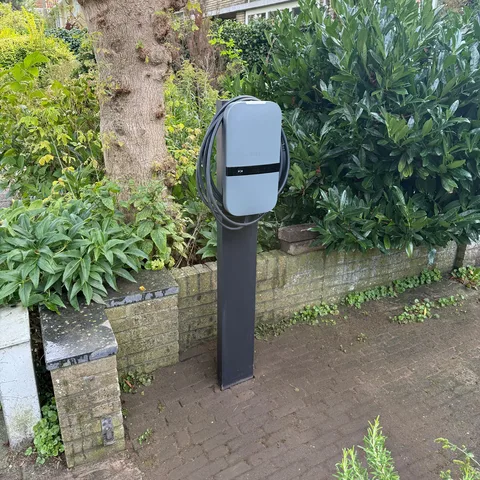Laadpaal op een paal met opgerolde laadkabel in een voortuin in Bilthoven