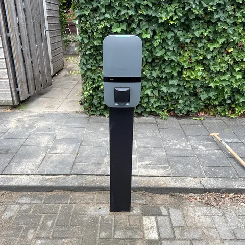 Peblar laadpaal op een paal naast een klimopheg op een oprit in Soest